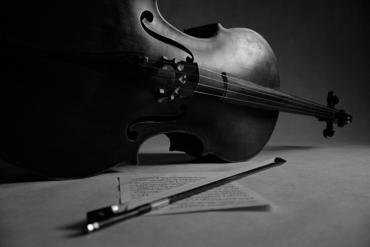 Czarno-biały detal wiolonczeli leżącej obok arkusza nut i smyczka, artystyczna fotografia studyjna wykonana w Katowicach przez Andrzeja Hanzlika.