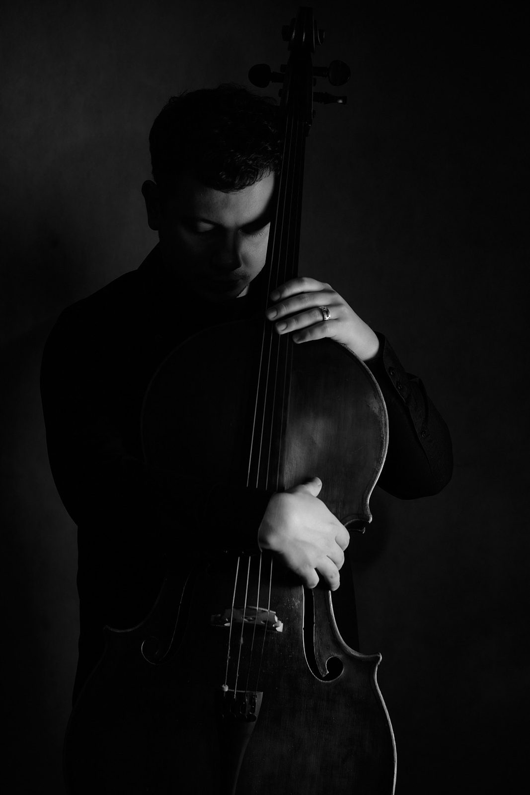 Czarno-biały portret młodego wiolonczelisty trzymającego instrument, profesjonalna sesja zdjęciowa w Katowicach, fot. Andrzej Hanzlik.